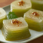 Steamed Pandan Tapioca Cakes sliced into layers on a white plate