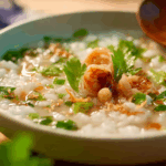 Thai Breakfast Rice Soup with shrimp and herbs close-up
