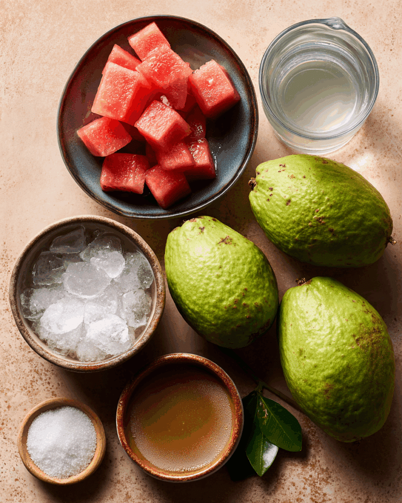 Flat lay of guavas, sugar, chilled water, and strainer for making guava drink