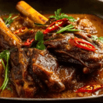 Lamb Shanks Massaman Curry served with rice and chili garnish.