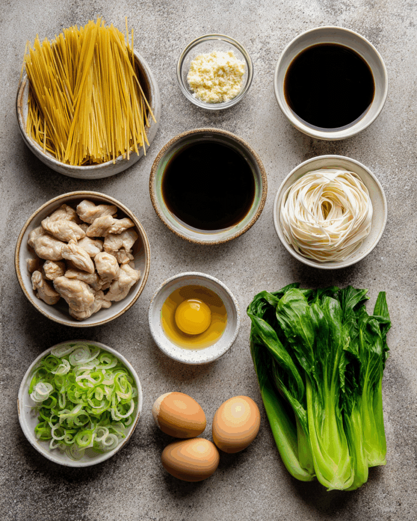 Flat lay of rice noodles, sauces, garlic, chicken, egg, and Chinese broccoli for Thai Stir Fried Noodles