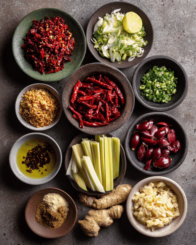 Ingredients for Thai Red Curry Paste arranged flat on a wooden surface.