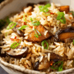Delicious baked mushroom rice served in a ceramic dish with golden mushrooms and herbs.
