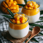 Coconut Panna Cotta with Mango Puree served in glass with mango topping.