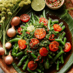 Thai Long Bean Salad Recipe served with lime and tomatoes on a wooden plate.