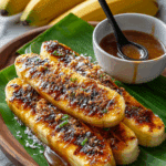 Thai Grilled Bananas With Coconut Caramel Sauce served with coconut flakes and caramel drizzle.