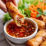 Homemade Thai spring roll dipping sauce in a small bowl with peanuts, carrots, and sliced chili