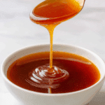 Finished sweet and tangy stir fry sauce in a glass bowl on a wooden table.