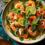 Finished spicy salmon sashimi salad on a plate with herbs and lime.