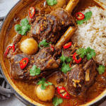 Lamb Shanks Massaman Curry served with rice and chili garnish.