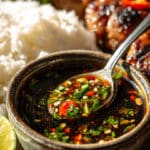 Thai dipping sauce served in a small bowl with fresh herbs and chili on a wooden table
